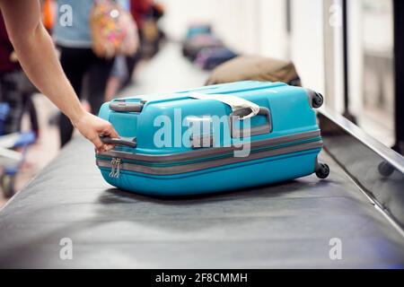 Suitcase on luggage conveyor belt carousel in the baggage claim at airport Stock Photo