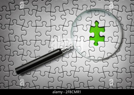 Searching for missing last puzzle piece with a magnifying glass Stock Photo