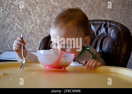 baby girl eating porridge from a bowl Stock Photo