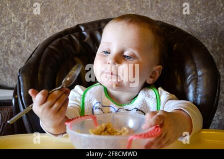 baby girl eating porridge from bowl Stock Photo