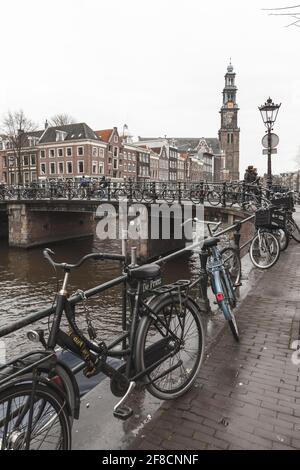 Amsterdam, Netherlands - February 24, 2017: Bicycles stand parked near canal coast in Amsterdam old town Stock Photo