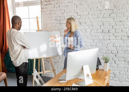 Serious multiracial colleagues working together on project in office, thinking about ideas for the startup. Concentrated business partners discussing Stock Photo