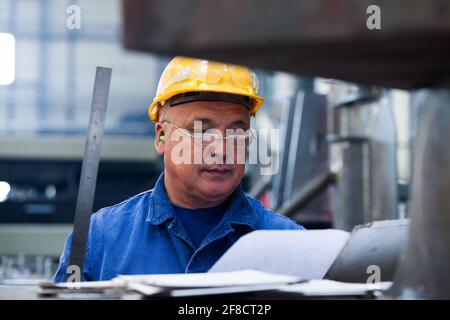 Kazakhstan, Nur-sultan. Locomotive-building plant. Asian worker's portrait in workshop. Focus on man. Blurred background. Stock Photo