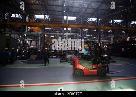 Kazakhstan, Nur-Sultan locomotive-building plant workshop. Worker on electric cart. Dark background. Stock Photo
