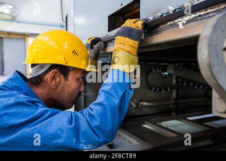 Kazakhstan, Nur-sultan. Locomotive-building plant. Asian workers portrait in workshop. Looks inside machine. Stock Photo