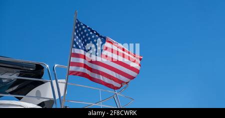 United states of America flag waving on yacht stern. Luxury boat moored at marina in Athens Greece. Blue sky background, copy space. Stock Photo