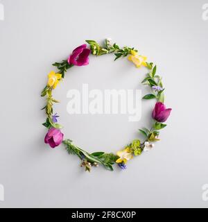 Beautiful round frame of colored flower. Circle of fresh flowers and leaves on light grey background. Top view, copy space. Stock Photo