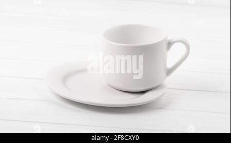 Empty cup standing on plate on white table Stock Photo