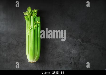 Green stalks of celery on a black stone background. Top view, free space Stock Photo