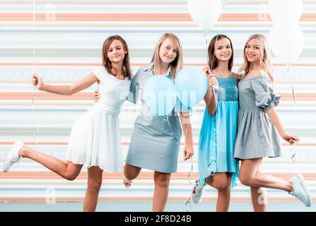 Beautiful girls in dresses holding balloons on striped background Stock Photo