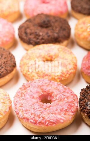 Colourful iced ring doughnuts with sprinkles. Stock Photo