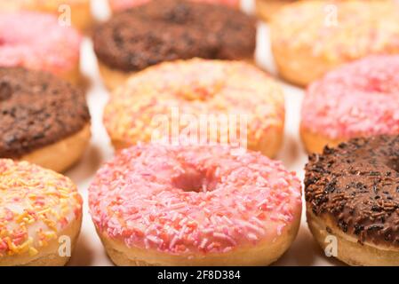 Colourful iced ring doughnuts with sprinkles. Stock Photo