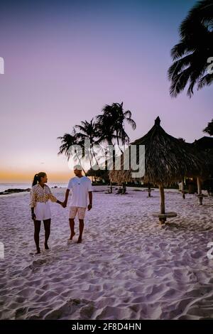 Sunset Aruba at Divi beach, colorful sunset at the beach in Aruba. couple men and woman mid-age Asian woman and European men on vacation Aruba Stock Photo