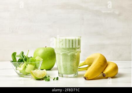 glass of green smoothie on kitchen table Stock Photo