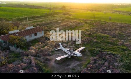 Abandoned broken plane in a field in countryside during sunset, aerial view Stock Photo
