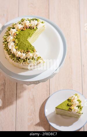 Matcha Mille Crepe Cake Presented On A Cake Holder With A Slice On A Plate Stock Photo