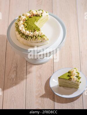 Matcha Mille Crepe Cake Presented On A Cake Holder With A Slice On A Plate Stock Photo