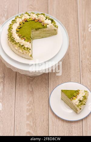 Matcha Mille Crepe Cake Presented On A Cake Holder With A Slice On A Plate Stock Photo