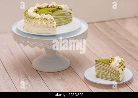 Matcha Mille Crepe Cake Presented On A Cake Holder With A Slice On A Plate Stock Photo