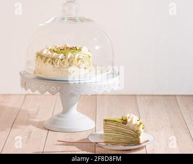 Matcha Mille Crepe Cake Presented On A Cake Holder With A Slice On A Plate. Stock Photo