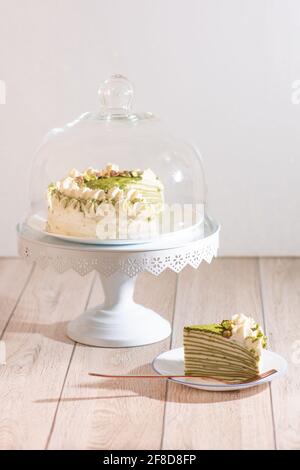 Matcha Mille Crepe Cake Presented On A Cake Holder With A Slice On A Plate Stock Photo