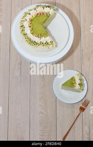 Matcha Mille Crepe Cake Presented On A Cake Holder With A Slice On A Plate. Stock Photo