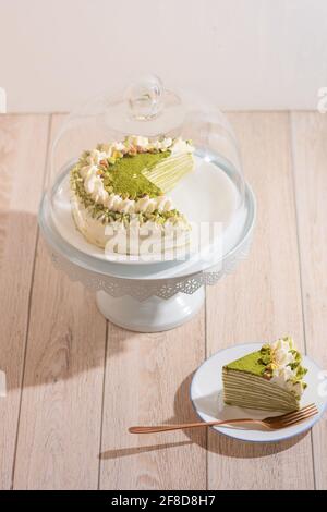 Matcha Mille Crepe Cake Presented On A Cake Holder With A Slice On A Plate Stock Photo