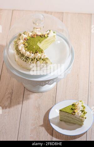 Matcha Mille Crepe Cake Presented On A Cake Holder With A Slice On A Plate Stock Photo