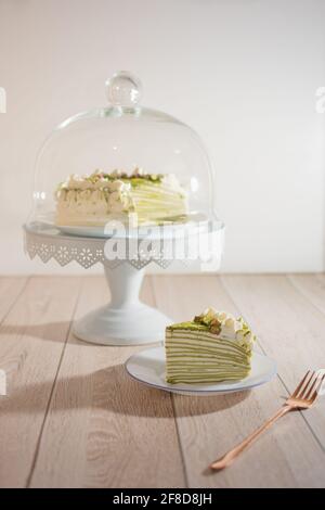 Matcha Mille Crepe Cake Presented On A Cake Holder With A Slice On A Plate Stock Photo