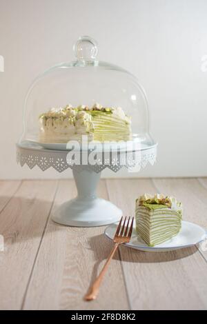 Matcha Mille Crepe Cake Presented On A Cake Holder With A Slice On A Plate Stock Photo