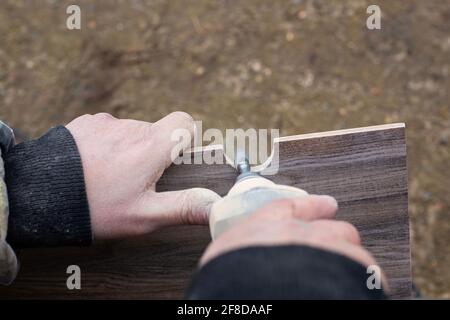 A man mills a hole in a ceramic tile for sanitary ware with a mini electric sander.Renovation and cladding of the bathroom. Stock Photo