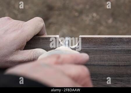 A man mills a hole in a ceramic tile for sanitary ware with a mini electric sander.Renovation and cladding of the bathroom. Stock Photo