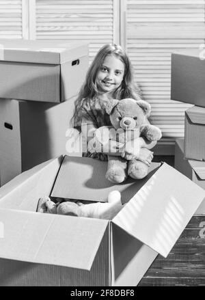 Moving routine. Only true friend. Girl child play with toy near boxes. Packaging things. Move out concept. Stressful situation. Divorce and separation Stock Photo