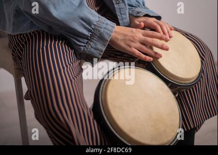 Close-up of female hands on mini bongo drums. The girl plays a traditional ethnic percussion instrument Stock Photo