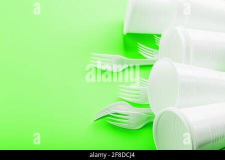 Plastic dishes on a green background with free space. Plastic waste separation and collection concept. Refusal from plastic Stock Photo