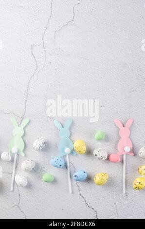 Easter greeting card with place for text.Decorative paper rabbits and Easter mini eggs, decorations on grey concrete background. Spring holidays conce Stock Photo