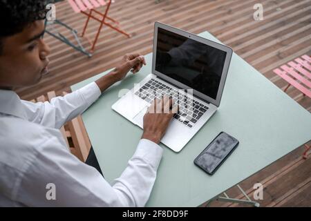 Top view of a black young man's workplace. Smartphone and laptop on the terrace. Work outside the office, remote work or study concept Stock Photo