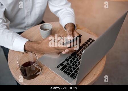 Top view of a black young man's workplace. Smartphone and laptop on the terrace. Work outside the office, remote work or study concept. Stock Photo