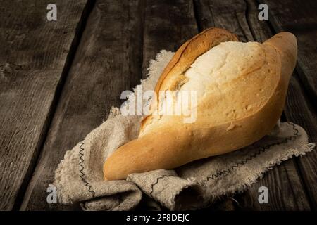 Freshly backed farmhouse bread on an old rustic wooden board. Retro style. Stock Photo