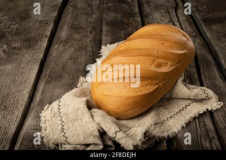 Freshly backed farmhouse bread on an old rustic wooden board. Retro style. Stock Photo