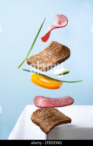 flying sausage sandwich on blue background and white table Stock Photo