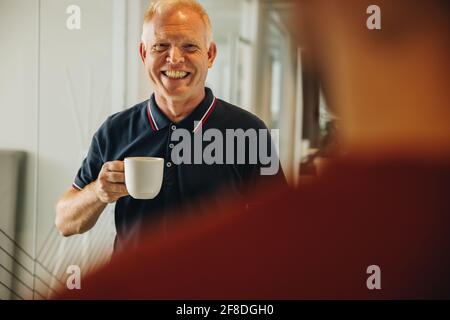 Senior businessman having a casual discussion during coffee break with colleagues. business people having a coffee break. Stock Photo