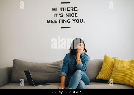 Executive sitting on sofa at lobby and thinking. Entrepreneur on sofa with hand on chin and looking away. Stock Photo