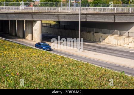 Blue car moving on a highway under an overpass bridge  Stock Photo
