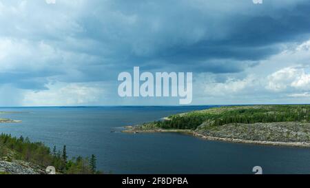 Seascape with Islands taken from a high point. Rain clouds in the sky. Northern changeable weather. Summer landscape in the White sea. Stock Photo