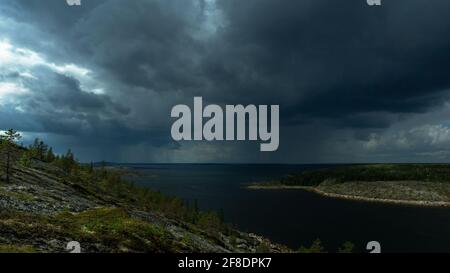Landscape with thunderclouds, dark clouds and an island in the sea. The image is in a low key. The element of nature in the open sea. Stock Photo