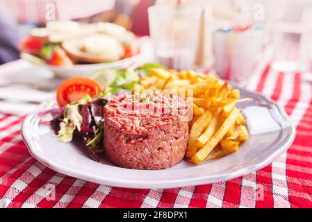 Steak Tartare with vegetables salad and french fries on dish Stock Photo