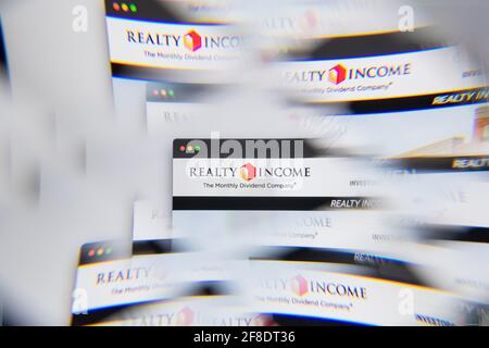 Milan, Italy - APRIL 10, 2021: Realty Income logo on laptop screen seen through an optical prism. Illustrative editorial image from Realty Income webs Stock Photo