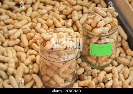 Peanuts in the shell are sold in the market. The measure of weighing with a glass jar. Close-up, full frame. The concept of harvesting, producing and Stock Photo