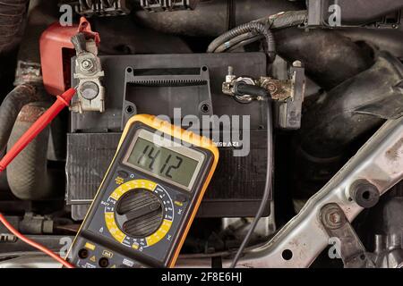 Checking car battery and alternator voltage with running engine Stock Photo